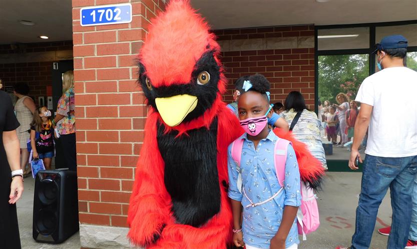 A cardinal mascot and student smile